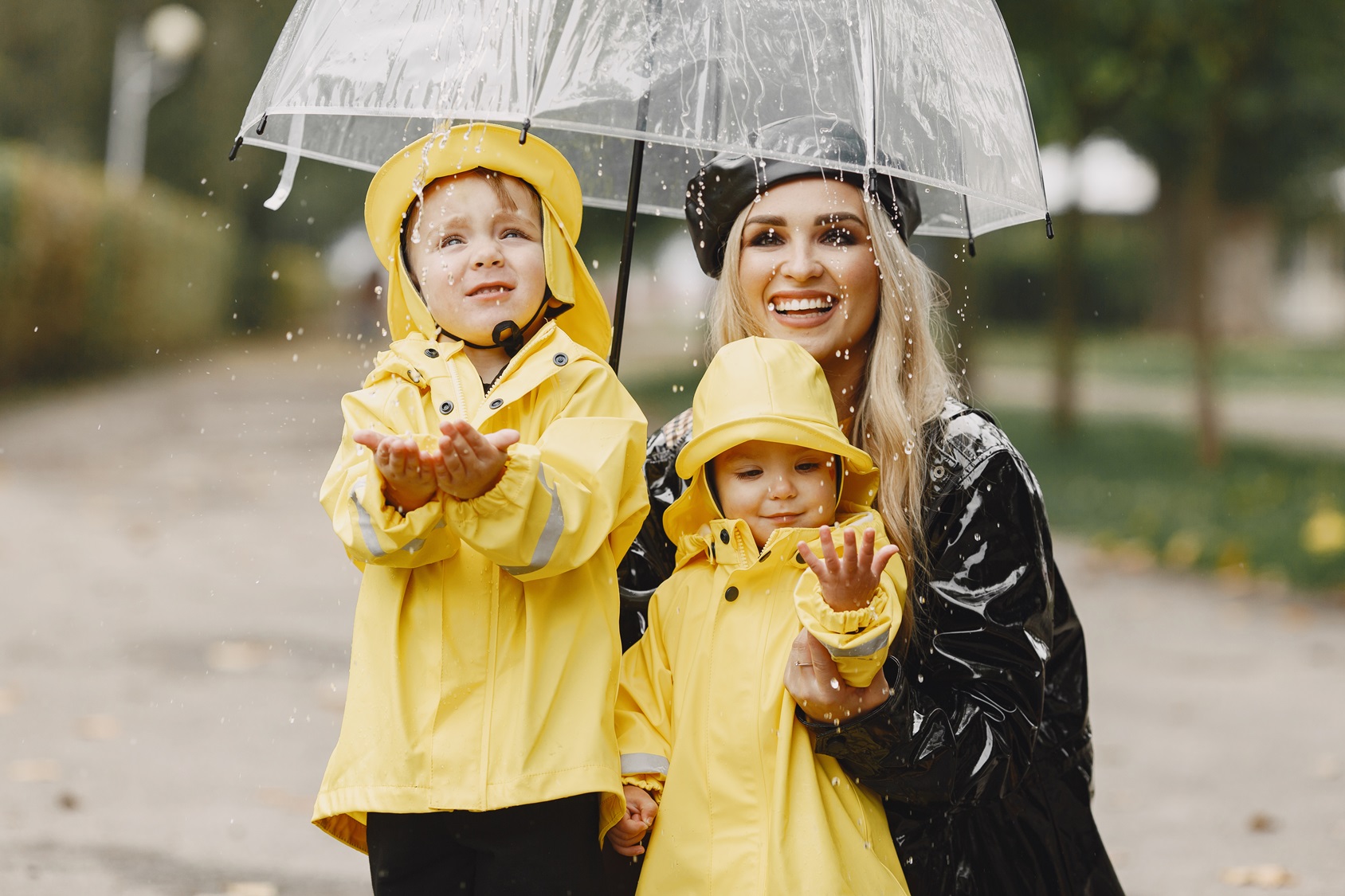 family-in-a-rainy-park-kids-in-a-yellow-raincoats-and-woman-in-a-black-coat