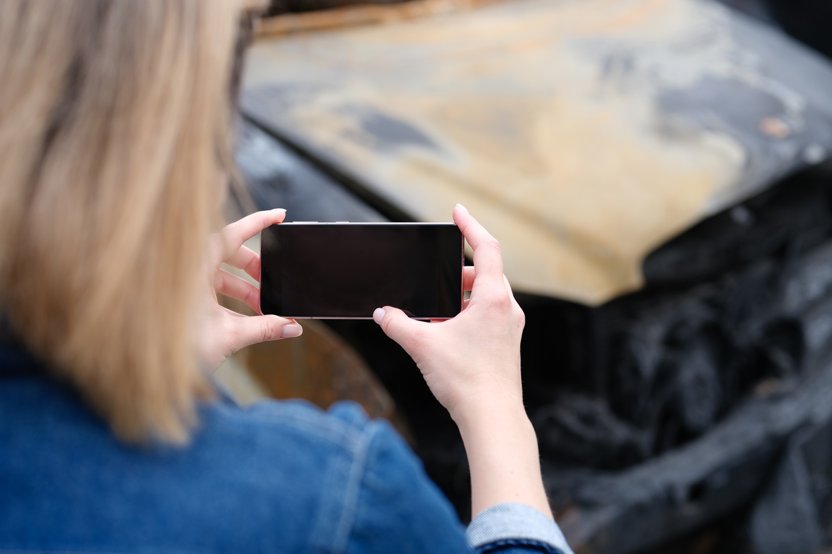 insurance-agent-woman-photographs-burnedout-car-on-smartphone